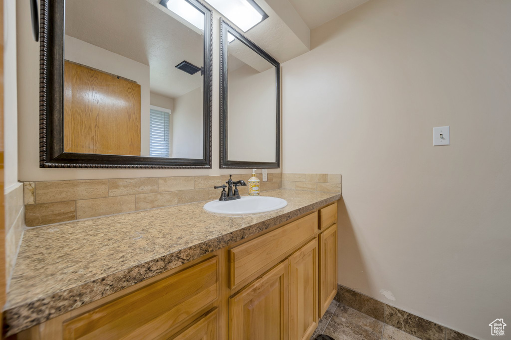 Bathroom featuring vanity, plenty of natural light, and baseboards