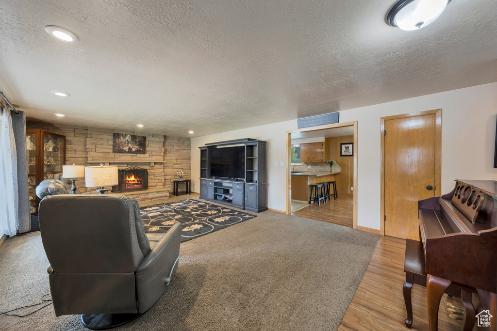 Living area featuring a textured ceiling, wood finished floors, a fireplace, baseboards, and recessed lighting