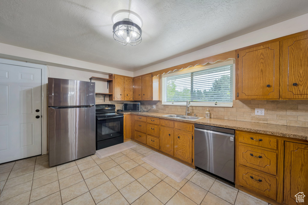 Kitchen with stainless steel appliances, a sink, open shelves, brown cabinetry, and tasteful backsplash