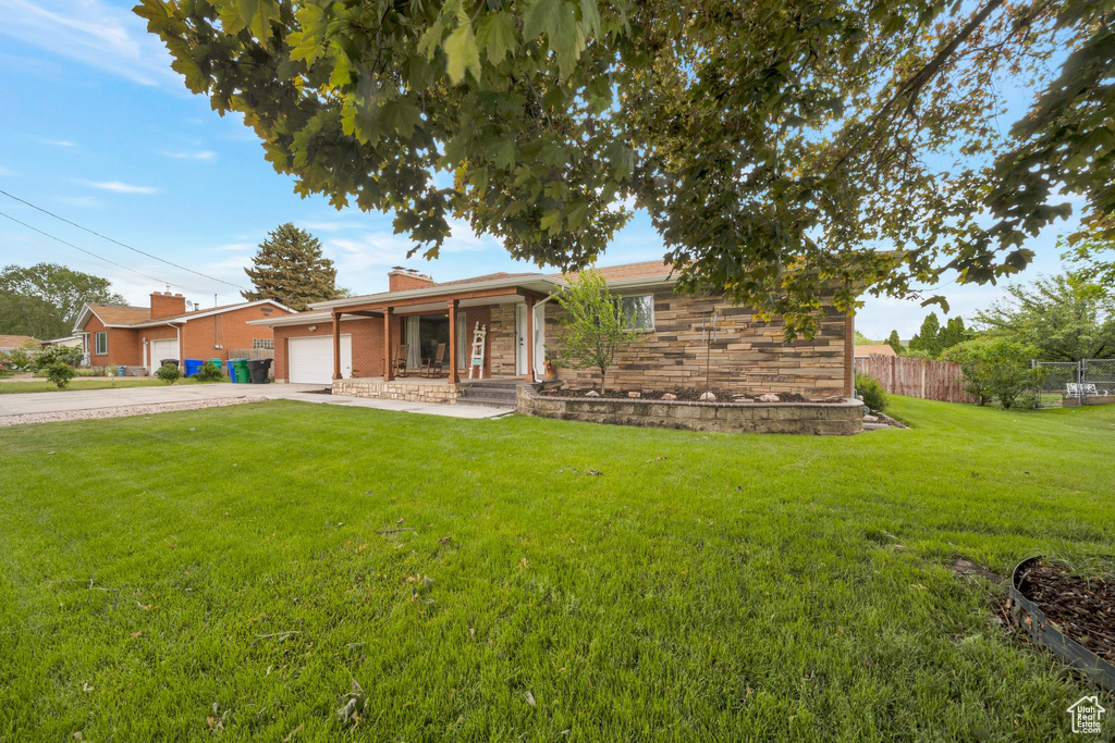 Ranch-style home with an attached garage, driveway, a chimney, a porch, and stone siding