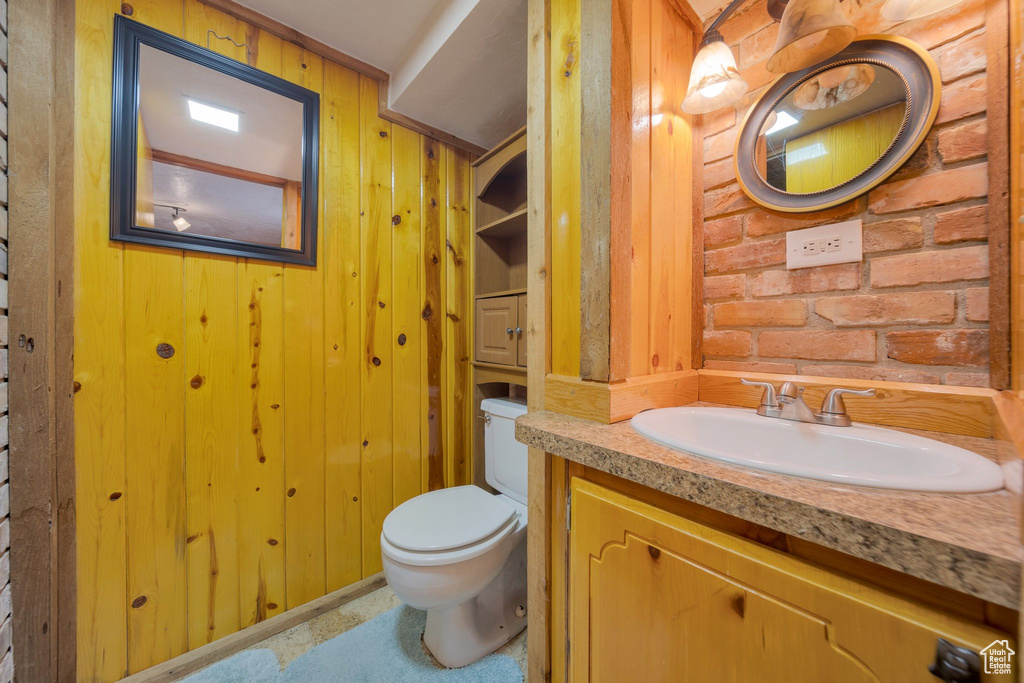 Bathroom featuring toilet, wood walls, and vanity