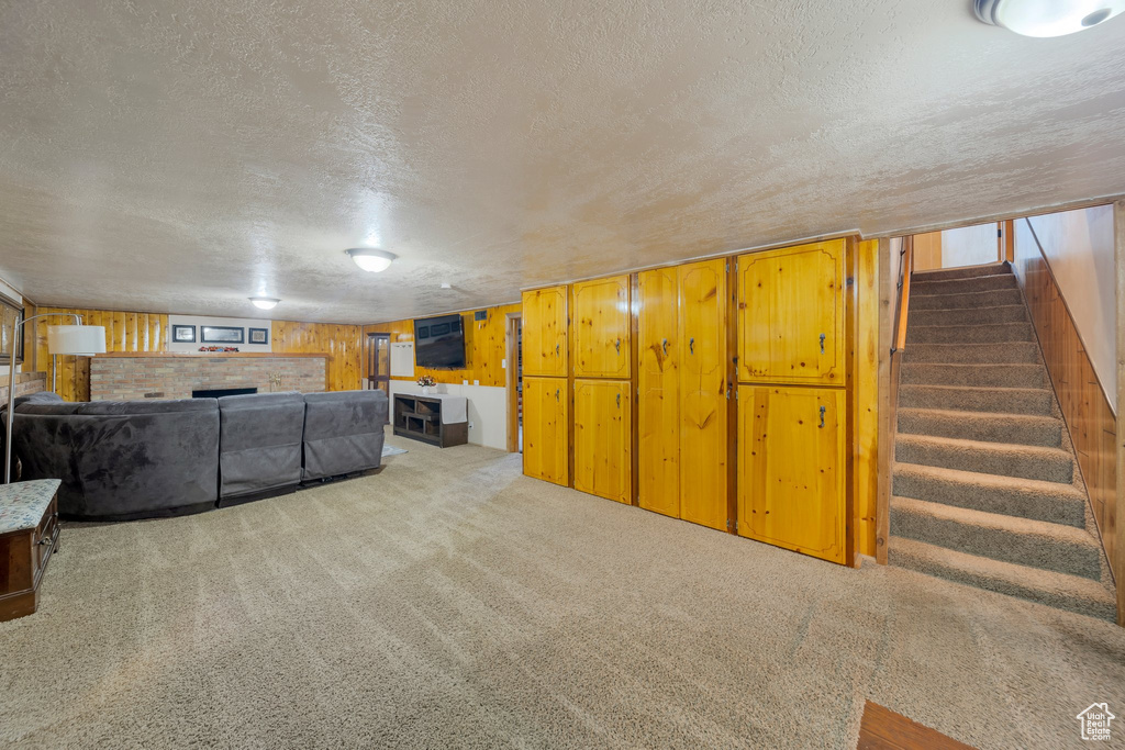Living area featuring a textured ceiling, stairs, a fireplace, carpet floors, and healthy amount of natural light