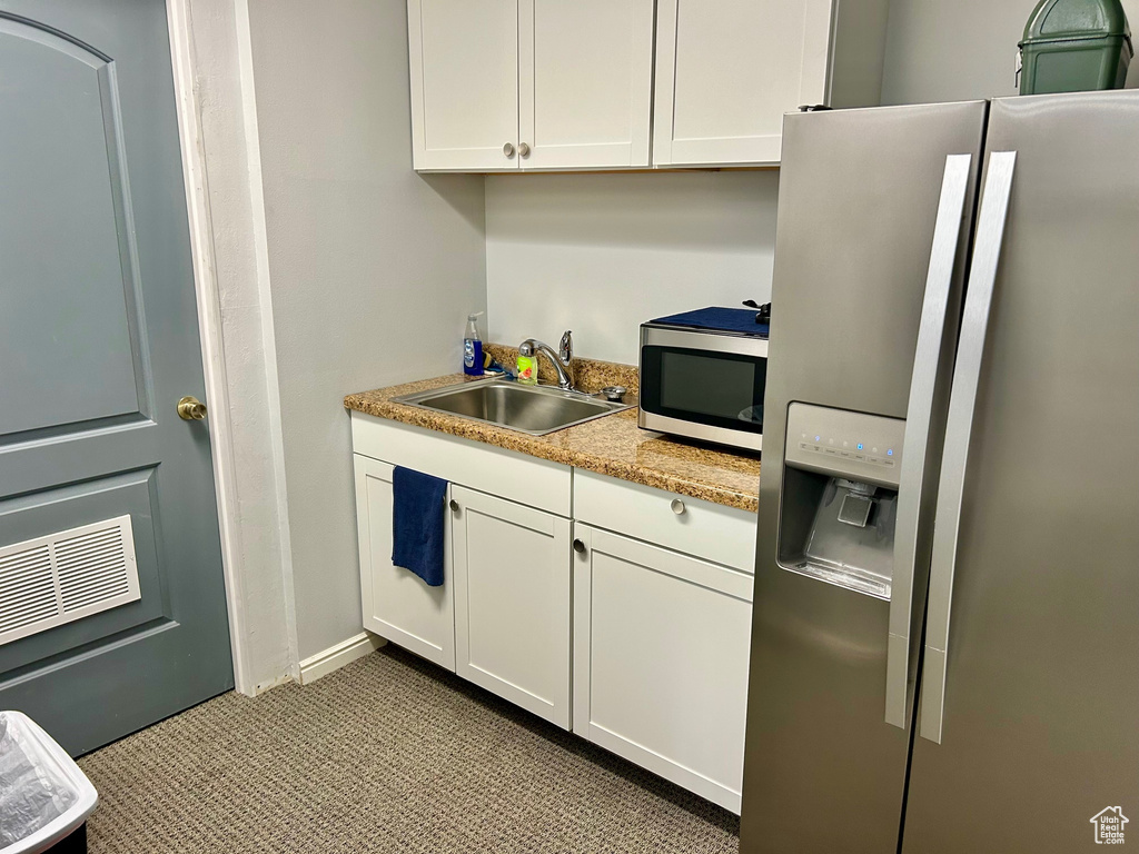 Kitchen with appliances with stainless steel finishes, a sink, and white cabinets
