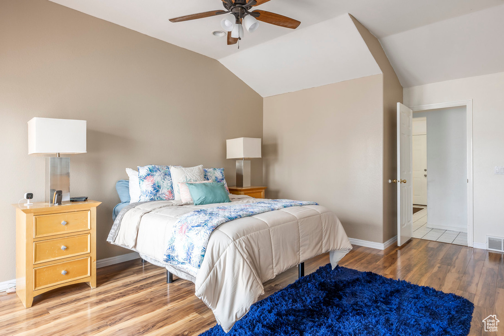 Bedroom featuring light wood-style flooring, vaulted ceiling, baseboards, and a ceiling fan