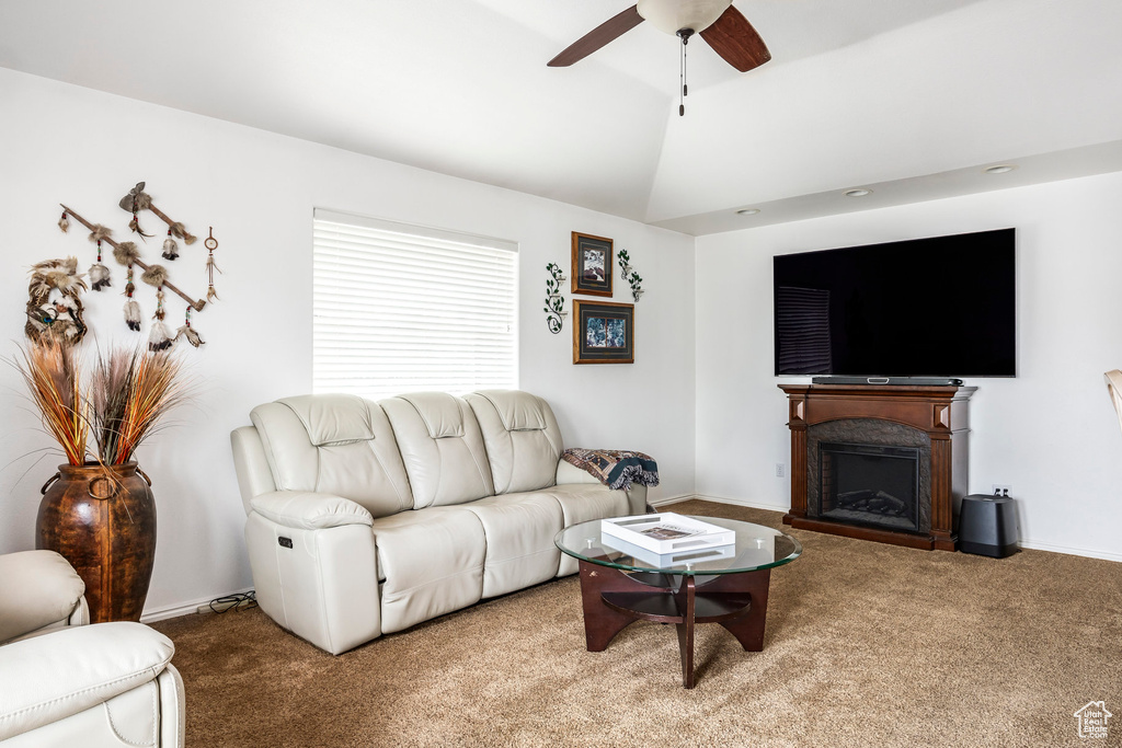 Carpeted living area with a ceiling fan, a fireplace, lofted ceiling, and baseboards