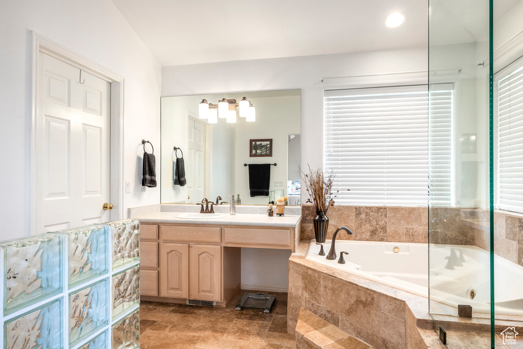 Bathroom with a jetted tub, vanity, and plenty of natural light