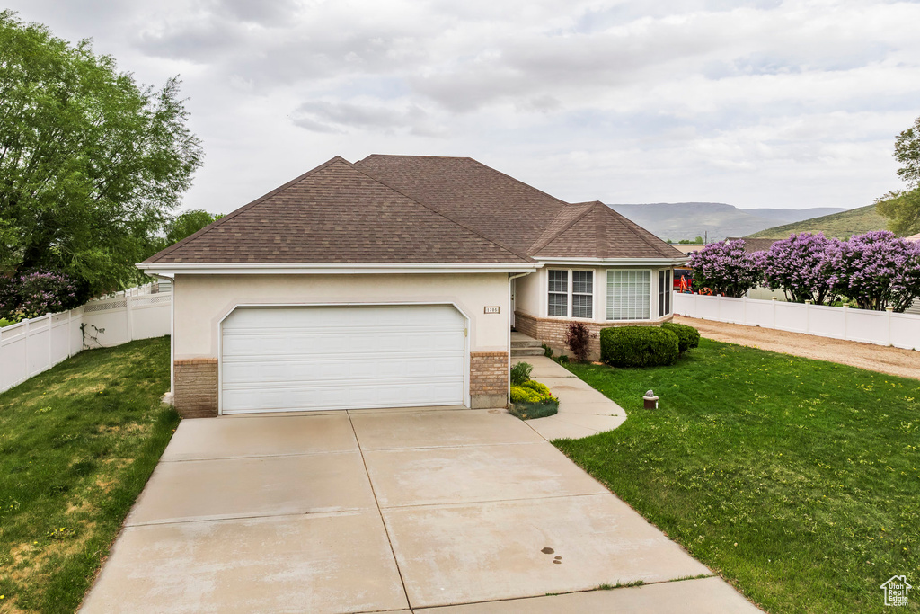 View of front of home with brick siding, roof with shingles, driveway, and an attached garage