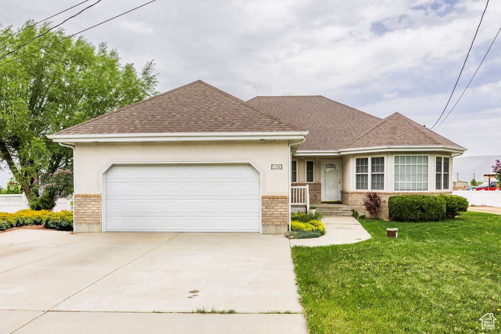 View of front facade with brick siding, concrete driveway, a shingled roof, a garage, and a front lawn