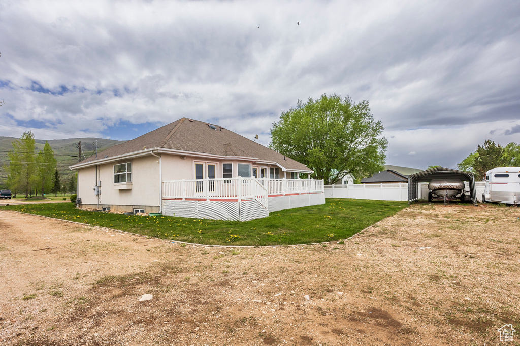 Rear view of house with a detached carport, stucco siding, and roof with shingles