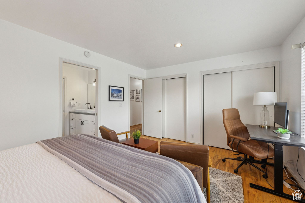 Bedroom with multiple closets, light wood-type flooring, a sink, recessed lighting, and a desk
