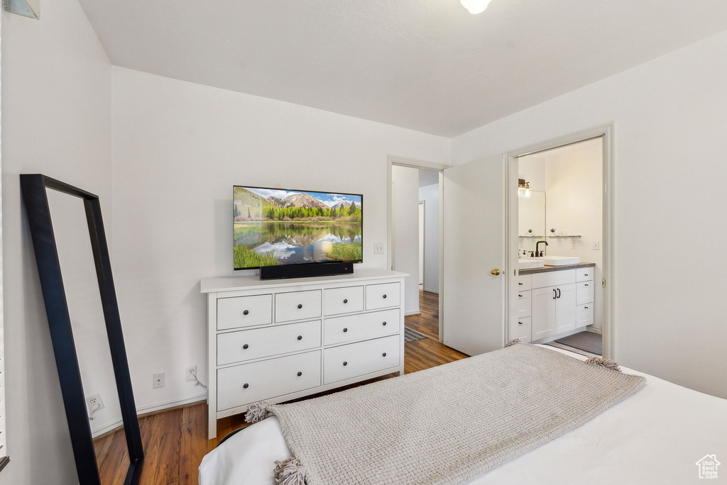 Bedroom featuring a sink, wood finished floors, and ensuite bathroom