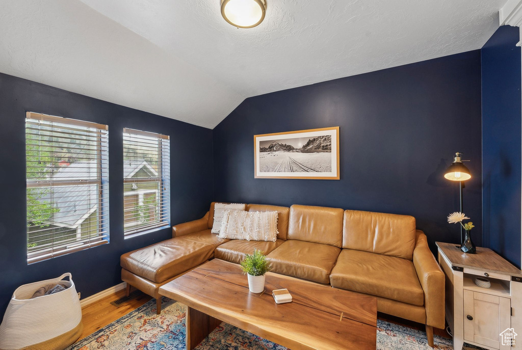Living room featuring wood finished floors, lofted ceiling, and baseboards
