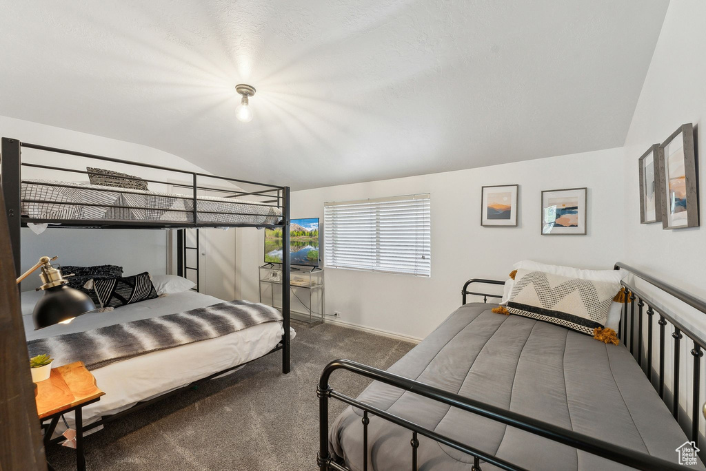 Bedroom featuring vaulted ceiling, carpet, and baseboards
