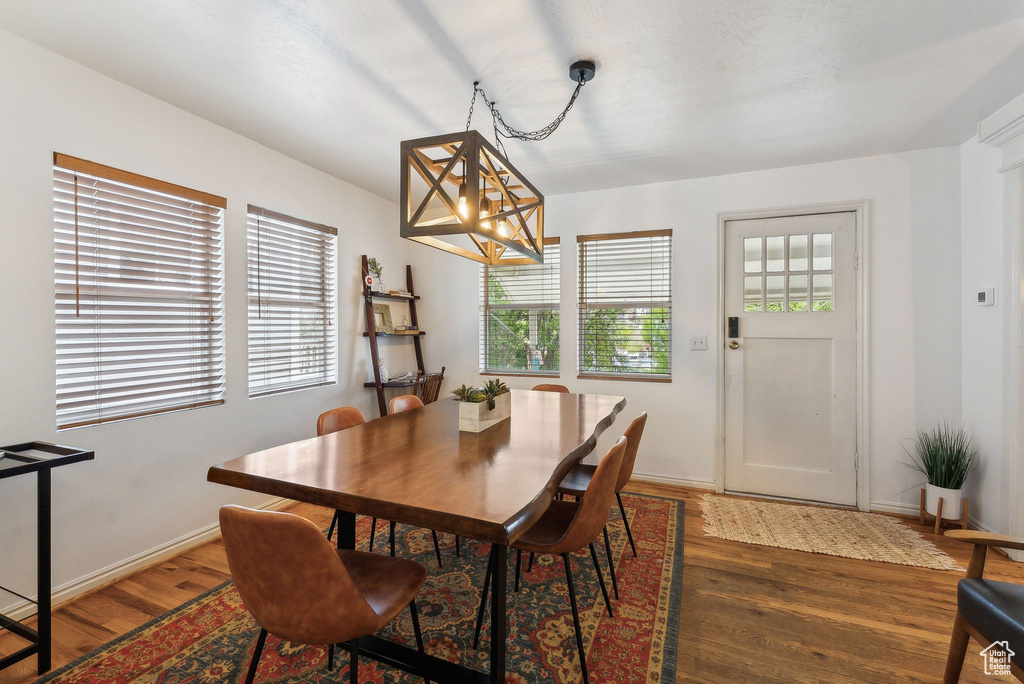 Dining space with wood finished floors, a chandelier, and baseboards