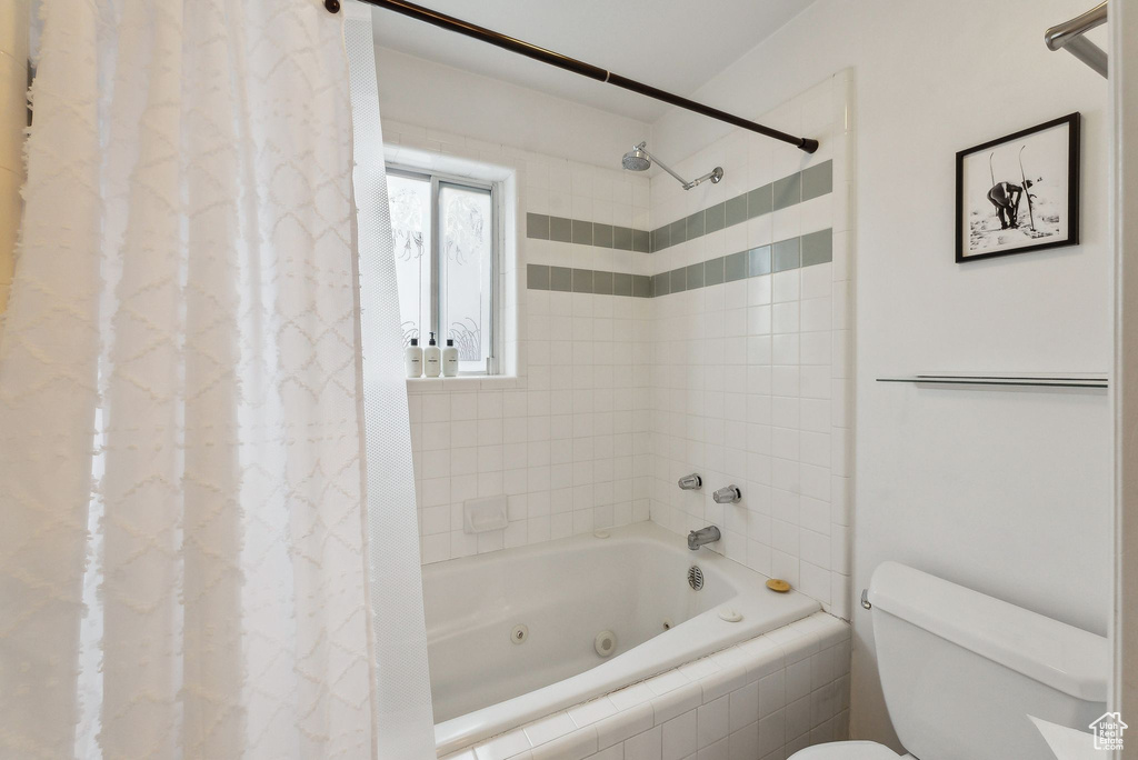 Bathroom with a combined bath / shower with jetted tub and toilet