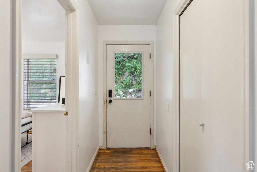 Doorway to outside featuring healthy amount of natural light, dark wood-type flooring, and baseboards