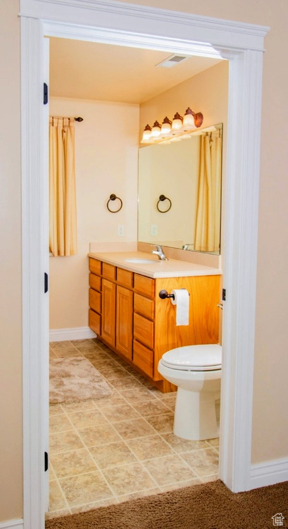 Bathroom featuring vanity, baseboards, toilet, and tile patterned floors