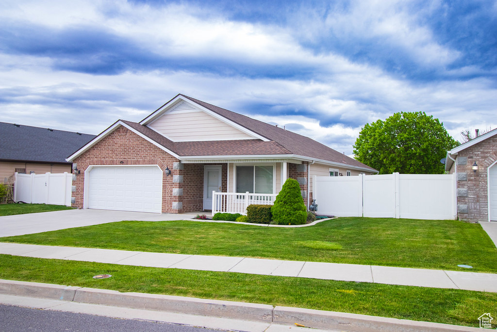 Ranch-style home with covered porch, brick siding, an attached garage, driveway, and a shingled roof