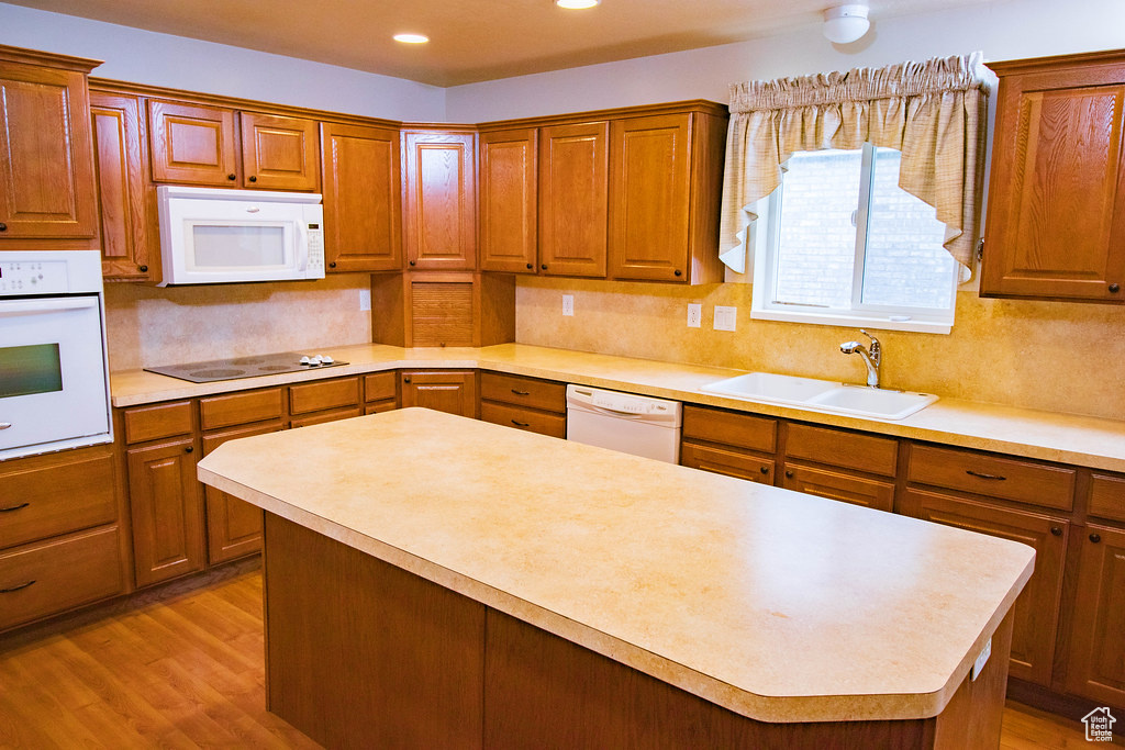 Kitchen featuring white appliances, a sink, light countertops, decorative backsplash, and recessed lighting