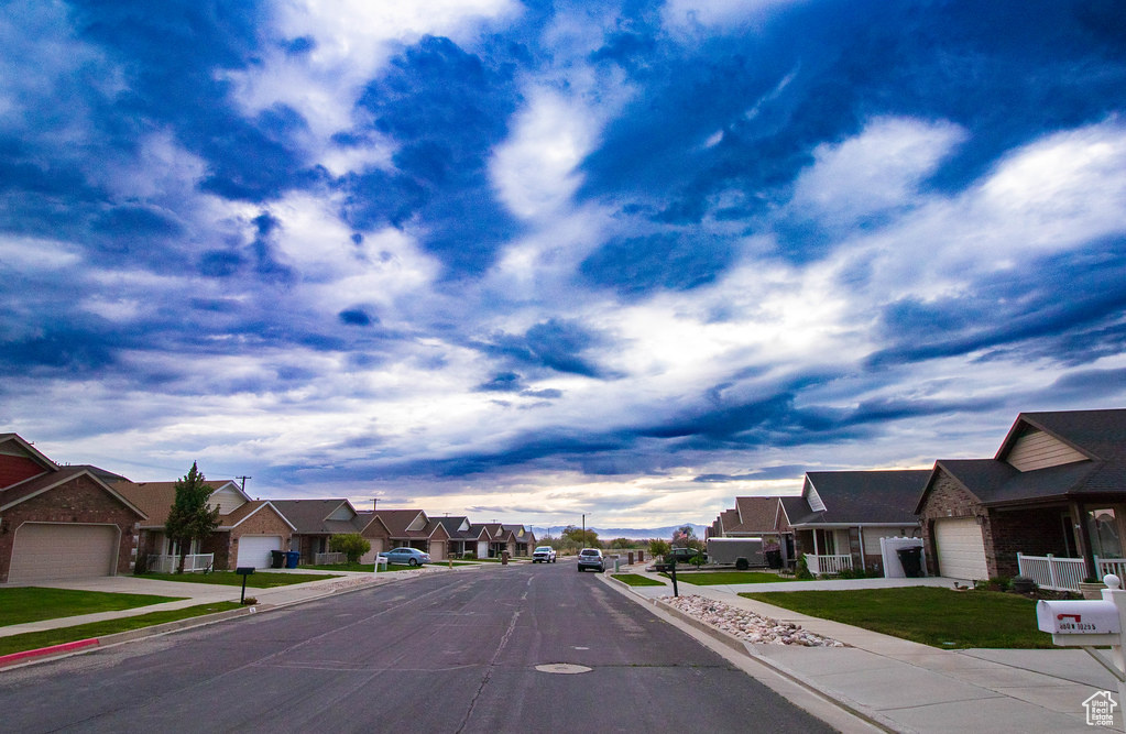 View of asphalt road featuring a residential view, curbs, and sidewalks