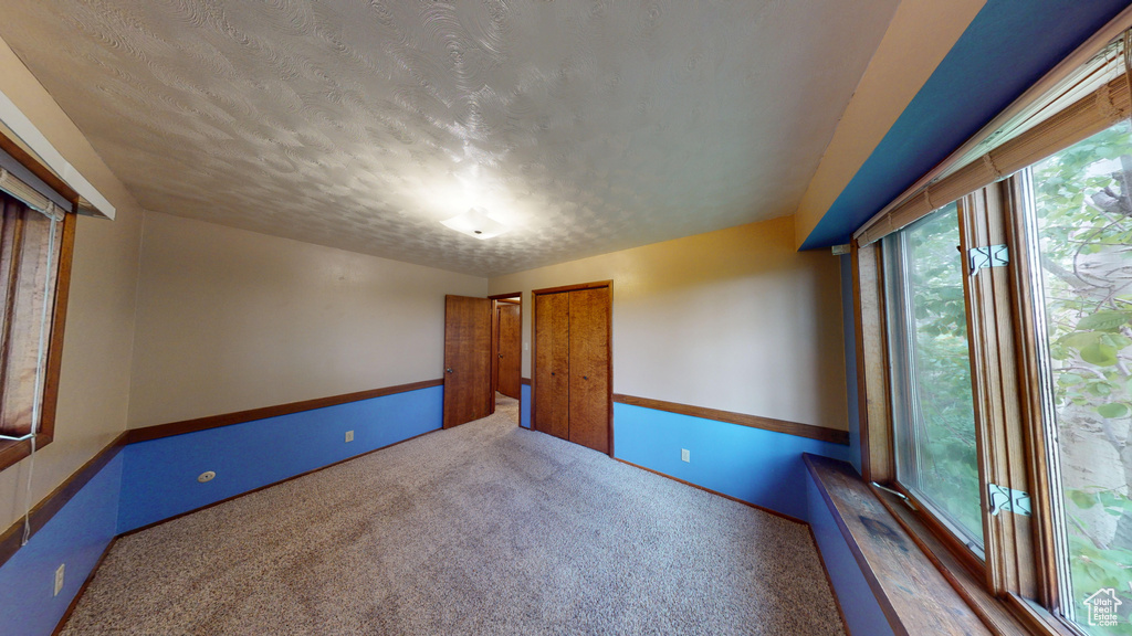 Spare room with carpet, a textured ceiling, and baseboards