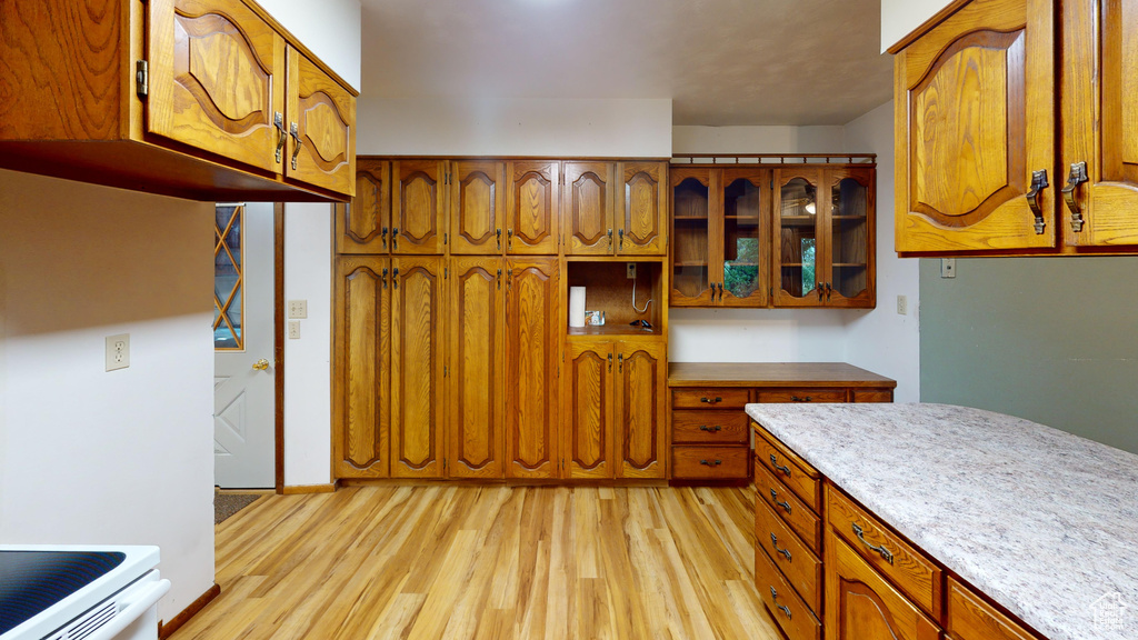 Kitchen featuring light wood-type flooring, brown cabinetry, and glass insert cabinets