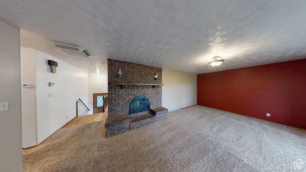 Unfurnished living room featuring carpet floors and a brick fireplace