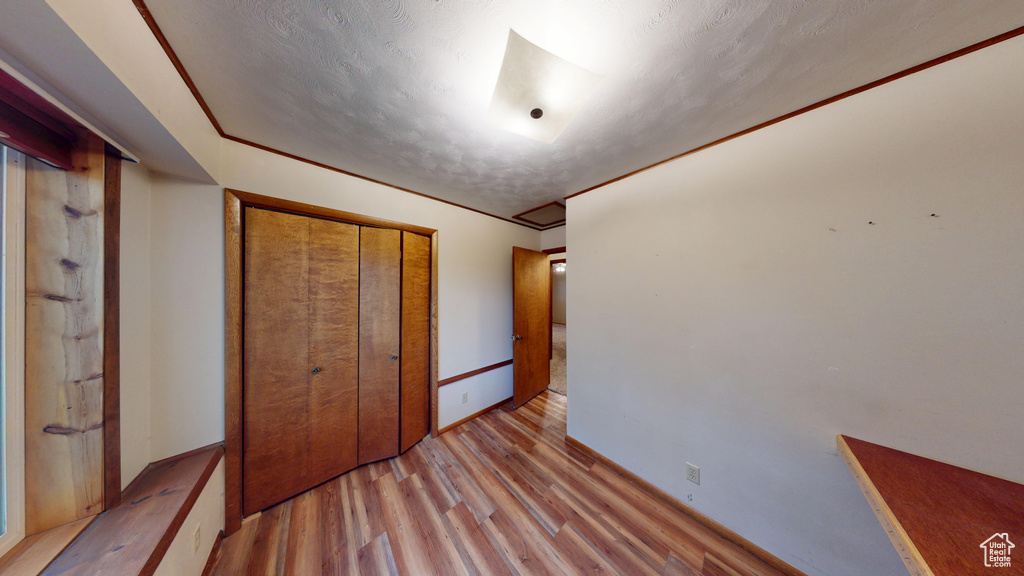 Unfurnished bedroom featuring light wood finished floors, a closet, and baseboards