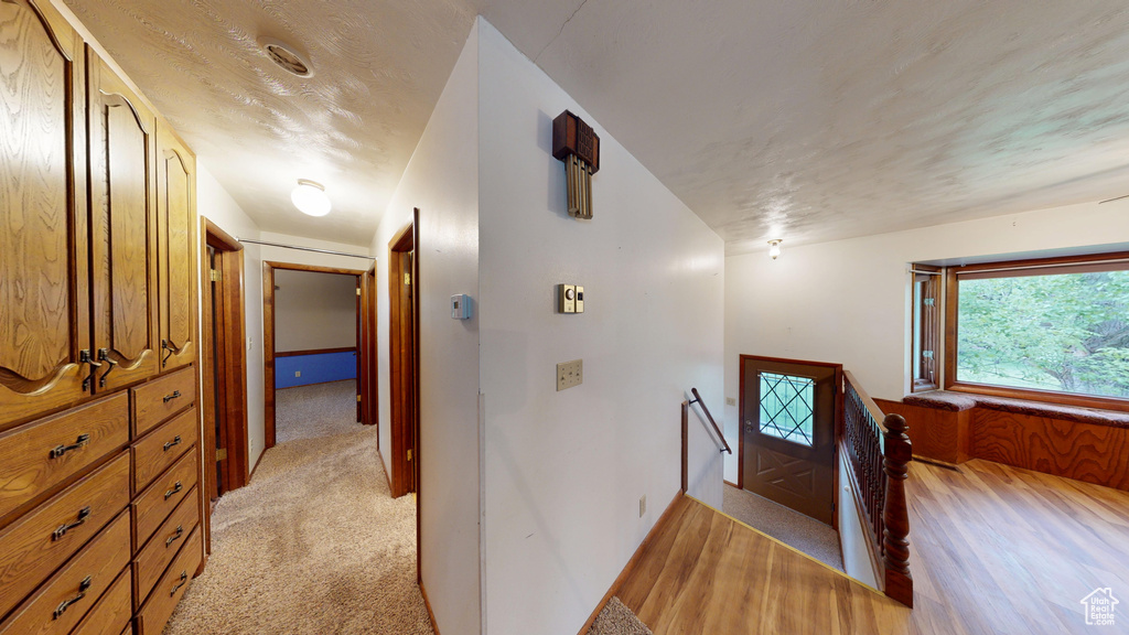 Hall featuring an upstairs landing, light carpet, and baseboards