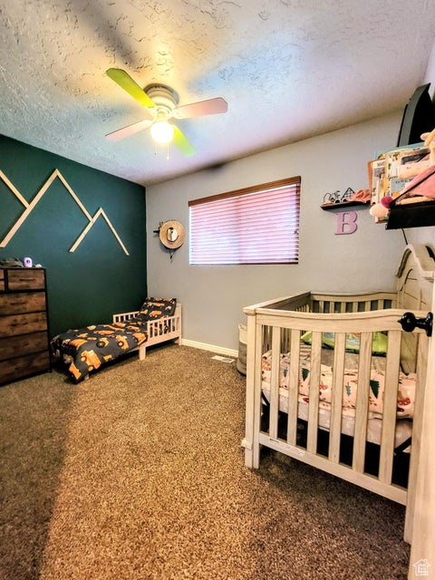 Bedroom featuring carpet floors, a textured ceiling, a ceiling fan, and baseboards