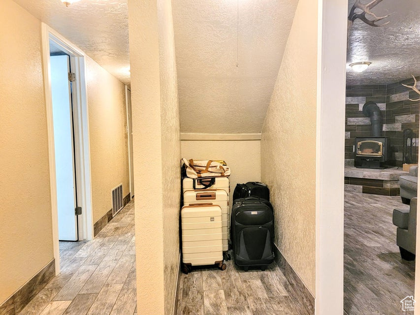 Detailed view of a textured wall, a textured ceiling, wood finished floors, and a wood stove