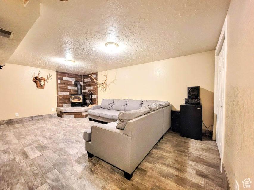 Living area with a textured ceiling, a wood stove, and wood finished floors