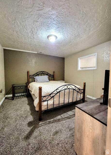 Bedroom featuring a textured ceiling, carpet, and baseboards