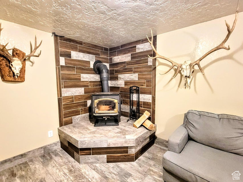Detailed view of a wood stove, wood finished floors, and a textured ceiling