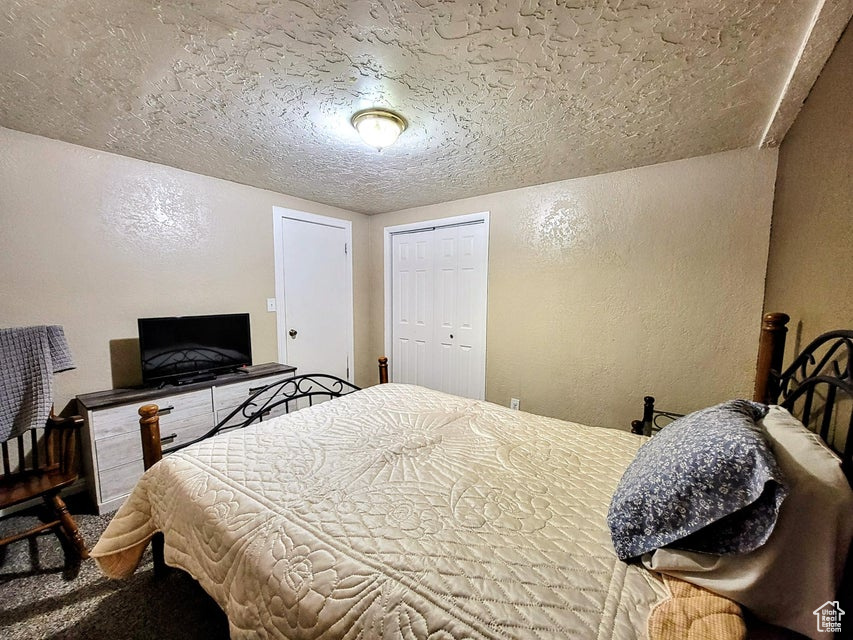 Bedroom featuring a textured wall, a textured ceiling, and a closet