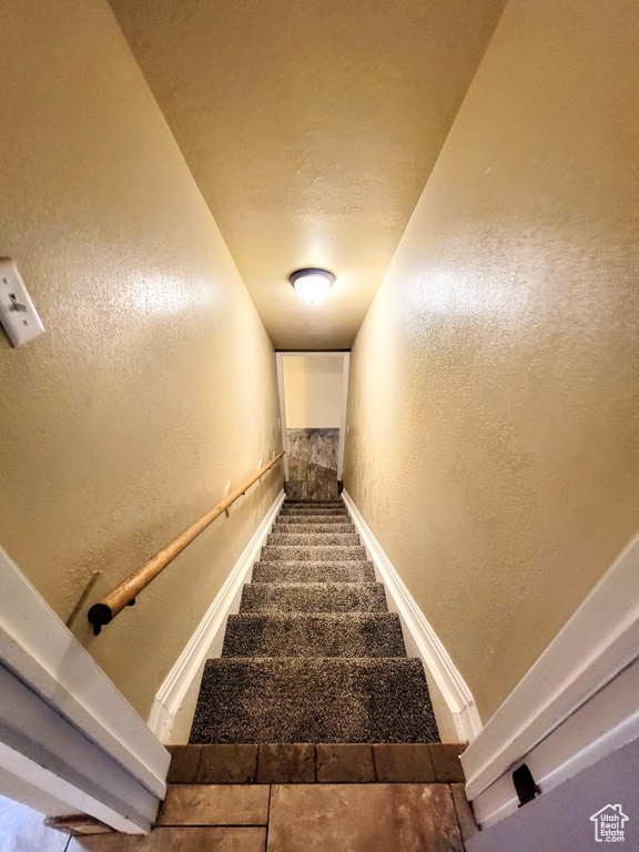 Stairway with a textured wall and baseboards