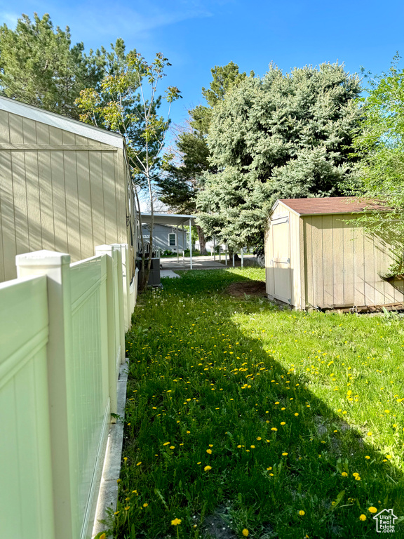 View of yard featuring fence, an outbuilding, and a shed