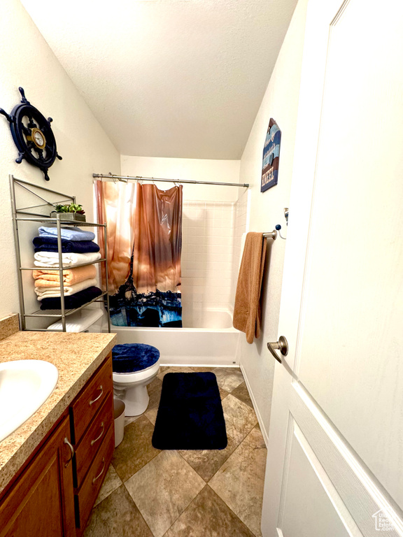 Full bath featuring vanity, a textured ceiling, shower / bath combo, and toilet