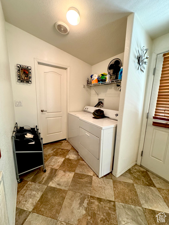 Laundry area featuring independent washer and dryer, a textured ceiling, stone finish flooring, and laundry area