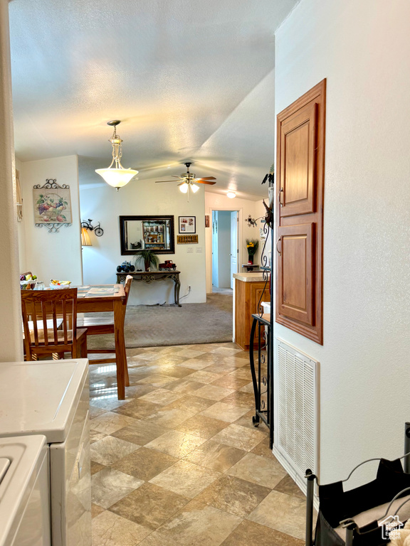 Dining space featuring visible vents, light colored carpet, a ceiling fan, independent washer and dryer, and vaulted ceiling