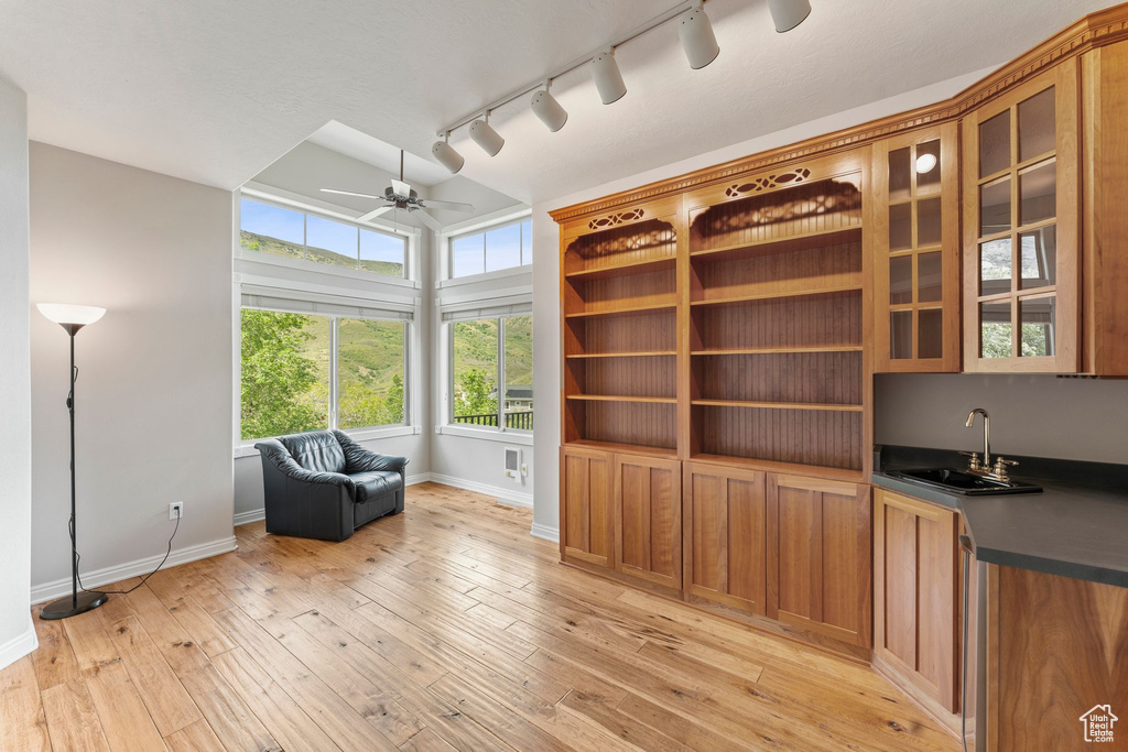 Living area with ceiling fan, rail lighting, baseboards, and light wood-style floors