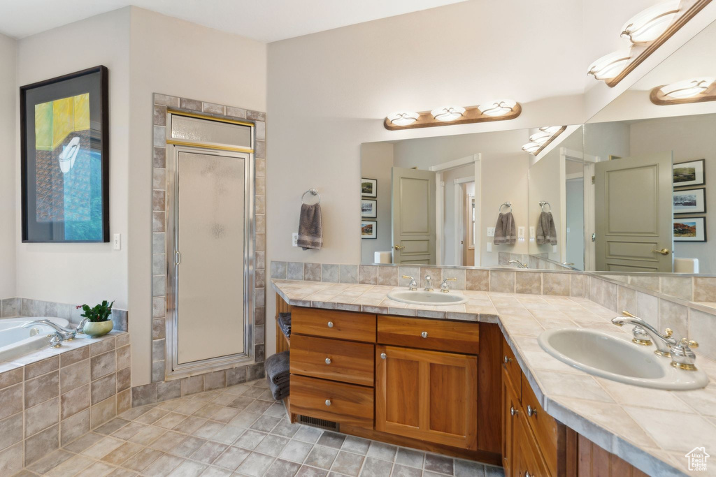 Full bathroom with a stall shower, double vanity, and a garden tub