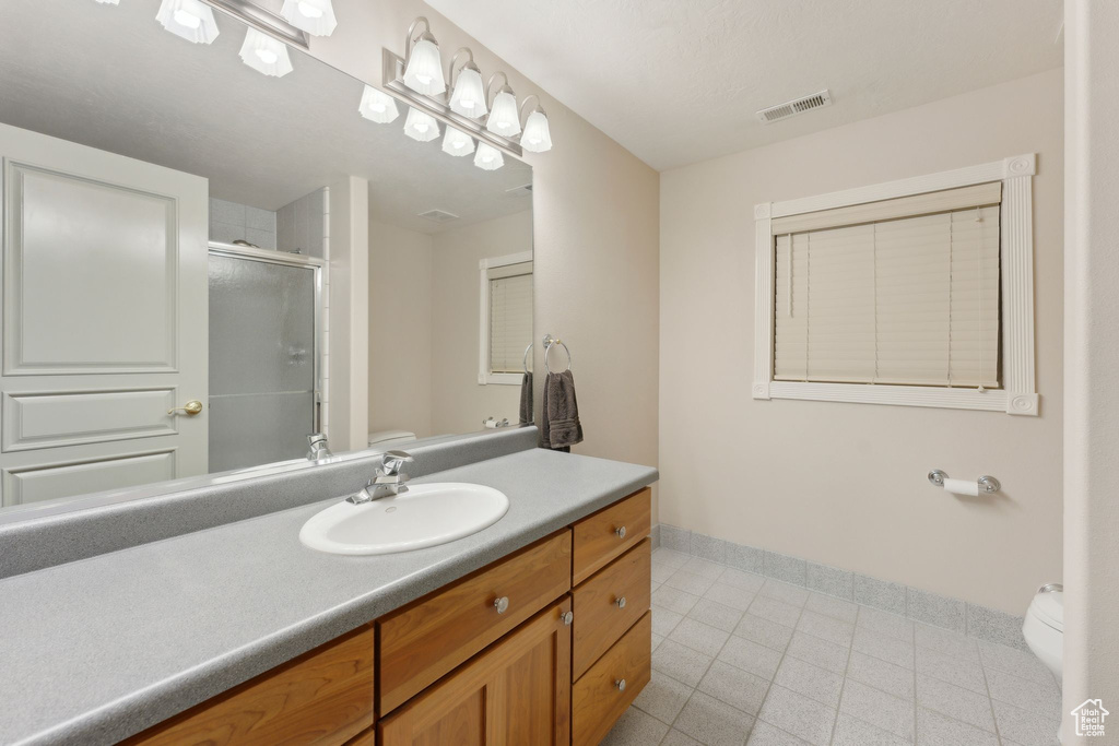 Full bath with toilet, baseboards, a stall shower, and vanity