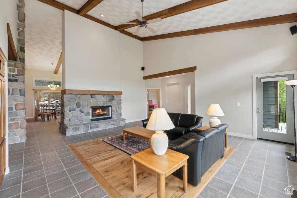 Living area with a fireplace, a high ceiling, a ceiling fan, tile patterned flooring, and beamed ceiling
