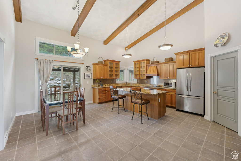 Kitchen with stainless steel appliances, high vaulted ceiling, a kitchen island, brown cabinets, and a kitchen breakfast bar