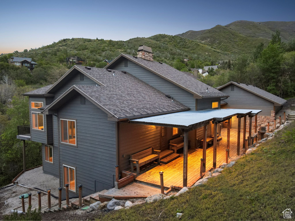 Rear view of house featuring a mountain view, a shingled roof, and a chimney