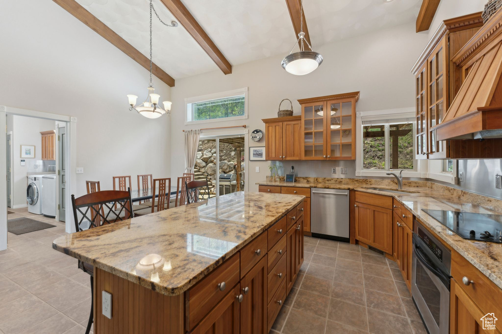 Kitchen with appliances with stainless steel finishes, a sink, a towering ceiling, brown cabinetry, and custom range hood