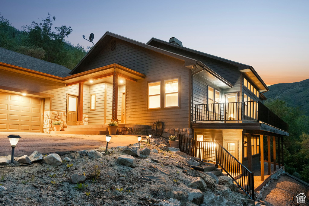 Back of house featuring an attached garage, stone siding, a chimney, stairway, and a mountain view