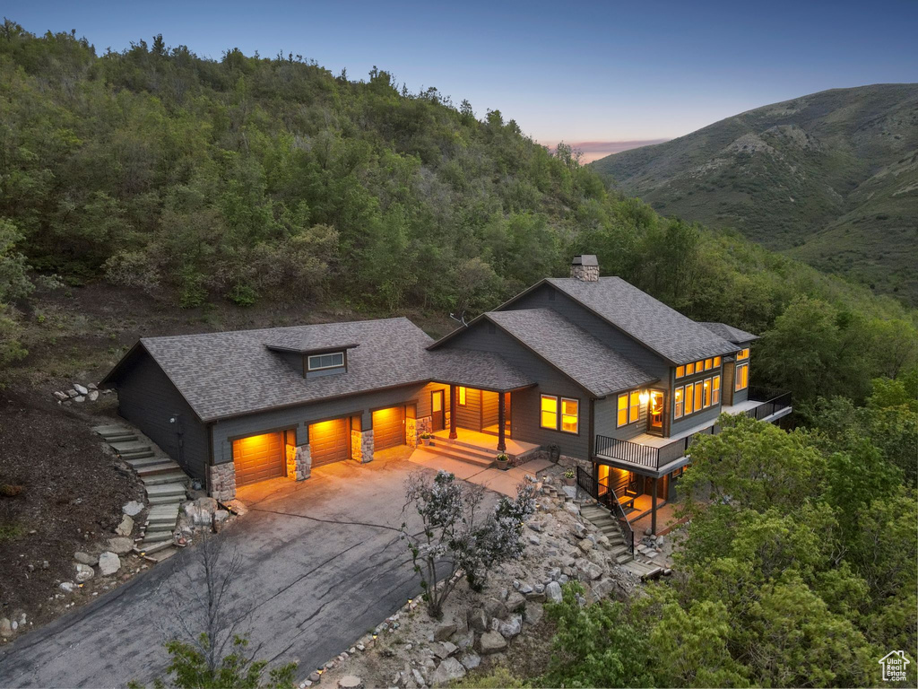 Back of property with roof with shingles, a garage, a chimney, and concrete driveway