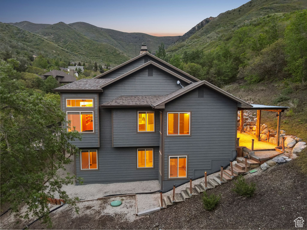 Back of house at dusk featuring a chimney and a mountain view